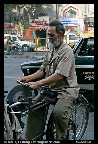 Man sharpening knifes on the street, Colaba. Mumbai, Maharashtra, India