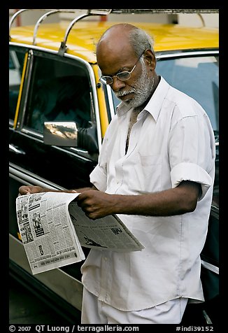 Man reading newspaper next to taxi. Mumbai, Maharashtra, India (color)