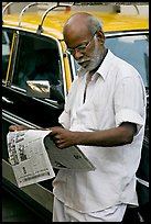 Man reading newspaper next to taxi. Mumbai, Maharashtra, India ( color)