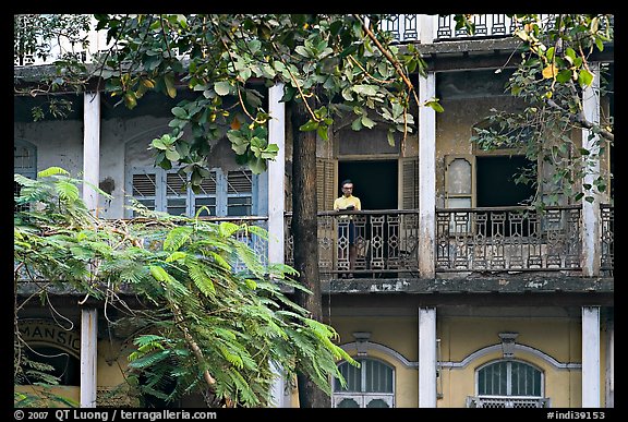 Facade with balconies and man reading. Mumbai, Maharashtra, India