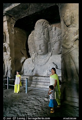 Woman and children standing in front of Mahesh Murti, main  Elephanta cave. Mumbai, Maharashtra, India (color)