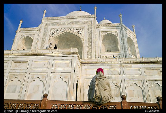 Woman sitting at the base of Taj Mahal looking up. Agra, Uttar Pradesh, India