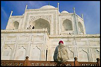 Woman sitting at the base of Taj Mahal looking up. Agra, Uttar Pradesh, India