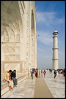 Couple sitting on side pishtaq and tourists strolling on platform, Taj Mahal. Agra, Uttar Pradesh, India