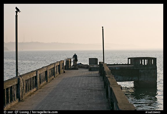 Pier with man fishing, early morning, Dona Paula. Goa, India