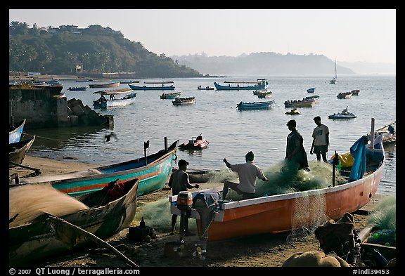 Picture/Photo: Men repairing net in small fishing boat, early morning, Dona  Paula. Goa, India