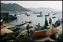 Men repairing net in small fishing boat, early morning, Dona Paula. Goa, India