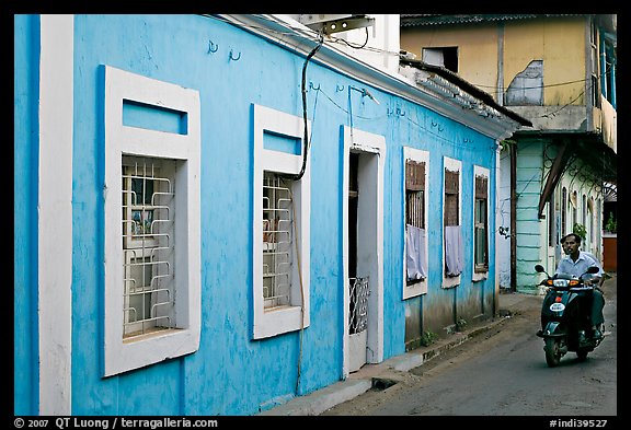 Men on motorbike driving through blue house, Panjim. Goa, India (color)