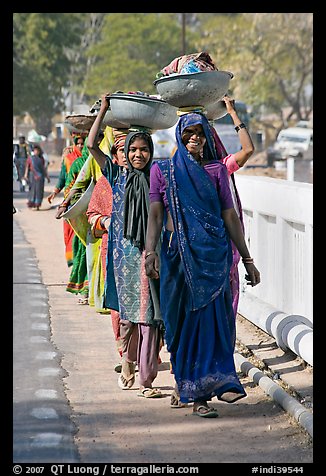 Women walking in line carrying baskets on heads. Khajuraho, Madhya Pradesh, India (color)