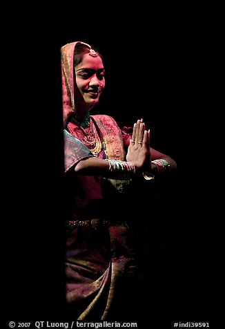 Woman joining hands in prayer gesture with dramatic lighting, Kandariya show. Khajuraho, Madhya Pradesh, India