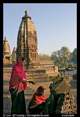 Women worshipping image with temple spire behind. Khajuraho, Madhya Pradesh, India