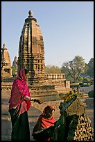 Women worshipping image with temple spire behind. Khajuraho, Madhya Pradesh, India ( color)