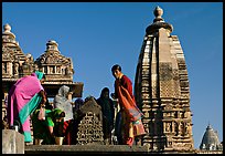 Women worshipping image with of Vahara and Lakshmana temples behind. Khajuraho, Madhya Pradesh, India (color)