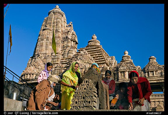 Worshippers making offering with Lakshmana temple behind. Khajuraho, Madhya Pradesh, India