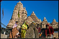 Worshippers making offering with Lakshmana temple behind. Khajuraho, Madhya Pradesh, India (color)