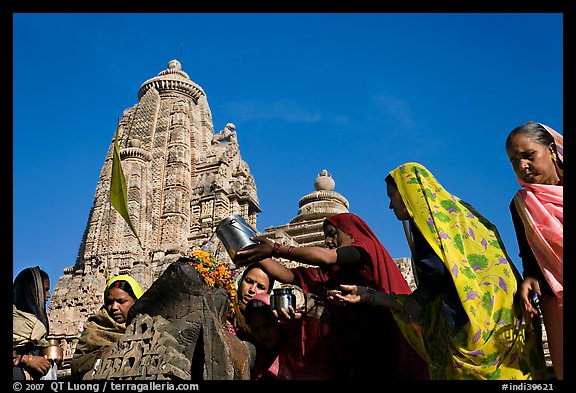 Hindu women making offerings to image with Lakshmana temple behind. Khajuraho, Madhya Pradesh, India (color)