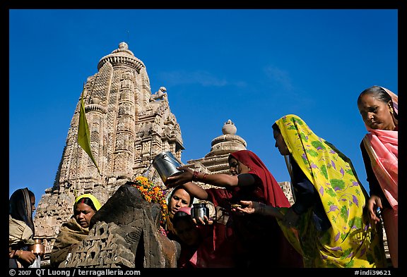 Hindu women making offerings to image with Lakshmana temple behind. Khajuraho, Madhya Pradesh, India