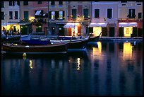 Light of shops reflected in harbor at dusk, Portofino. Liguria, Italy (color)