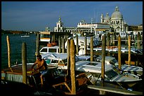 Water taxi driver cleaning out his boat in the morning, Santa Maria della Salute in the background. Venice, Veneto, Italy (color)