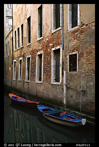 Small boats moored along a wall in a small side canal. Venice, Veneto, Italy