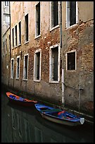 Small boats moored along a wall in a small side canal. Venice, Veneto, Italy