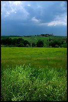 Field and distant village under storm skies. Tuscany, Italy ( color)