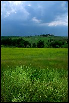 Field and distant village under storm skies. Tuscany, Italy (color)