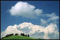 Fluffy clouds above ridge with cypress trees and house. Tuscany, Italy (color)