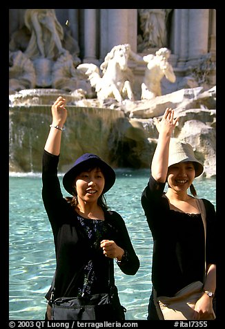 Asian tourists toss a coin over their shoulder into the Trevi Fountain. Rome, Lazio, Italy