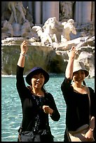 Asian tourists toss a coin over their shoulder into the Trevi Fountain. Rome, Lazio, Italy (color)