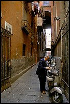 Man locking his motorbike in a side street. Naples, Campania, Italy ( color)