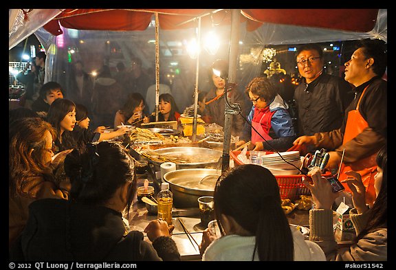 People eating noodles in a tent at night. Seoul, South Korea (color)