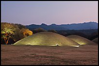 Illuminated tumuli at dusk and hills. Gyeongju, South Korea (color)