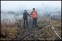 Couple hiking holding hands in fog. Jeju Island, South Korea