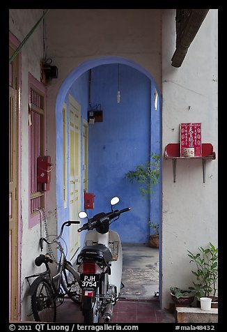 Motorcycle and altar outside townhouse. George Town, Penang, Malaysia
