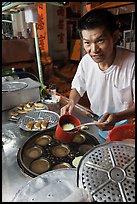 Man preparing mini-pancakes. George Town, Penang, Malaysia (color)