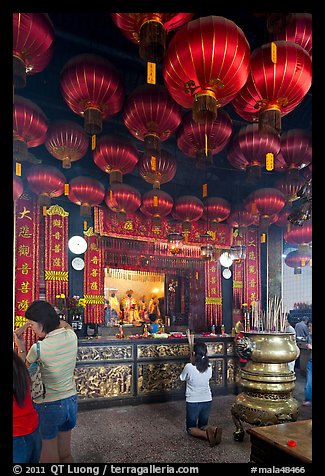 Woman in prayer, altar and lanters, Kuan Yin Teng temple. George Town, Penang, Malaysia (color)