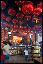 Woman in prayer, altar and lanters, Kuan Yin Teng temple. George Town, Penang, Malaysia (color)