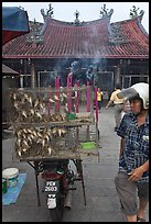 Motorcycle loaded with cage of birds (to be freed) in front of temple. George Town, Penang, Malaysia