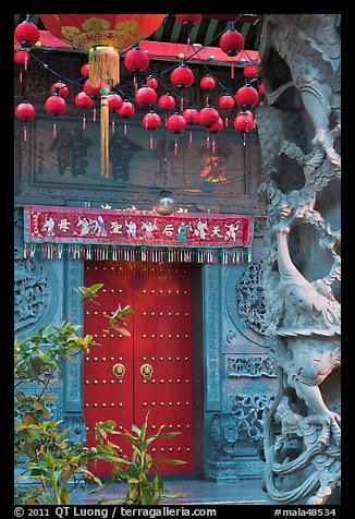 Red paper lanters, door, and stone carved wall, Hainan Temple. George Town, Penang, Malaysia