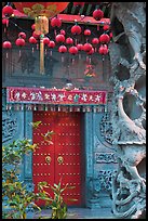 Red paper lanters, door, and stone carved wall, Hainan Temple. George Town, Penang, Malaysia