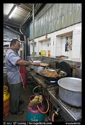 Man frying food in large pan. George Town, Penang, Malaysia