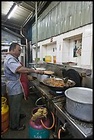 Man frying food in large pan. George Town, Penang, Malaysia