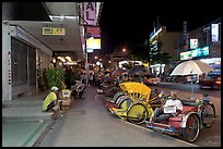 Cycle rickshaws lined on street at night. George Town, Penang, Malaysia