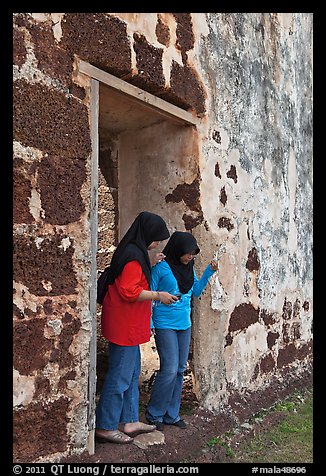 Malay girls exit on St Paul church doorway. Malacca City, Malaysia (color)