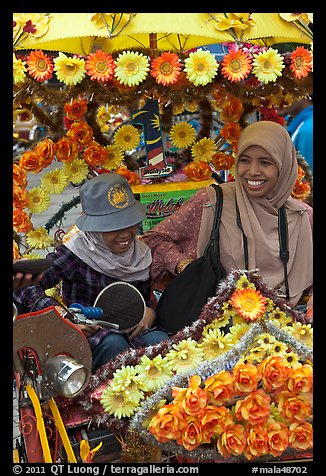 Mother and child riding decorated trishaw. Malacca City, Malaysia