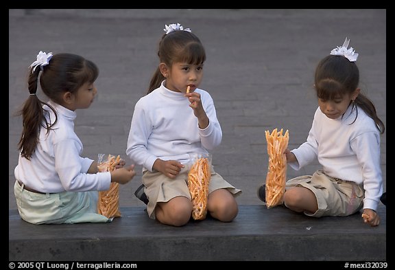 Three little girls in school uniform eating snack. Guadalajara, Jalisco, Mexico (color)