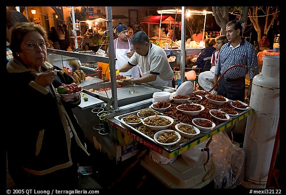 Woman eating by a street food stand , Tlaquepaque. Jalisco, Mexico