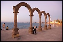 Boy standing by the Malecon arches at dusk, Puerto Vallarta, Jalisco. Jalisco, Mexico