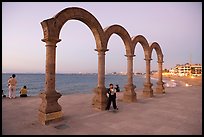 Boy standing by the Malecon arches at dusk, Puerto Vallarta, Jalisco. Jalisco, Mexico (color)